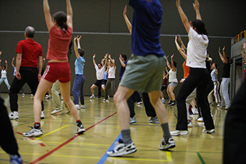 Leute in Sportbekleidung machen Gymnastik in einer Sporthalle.